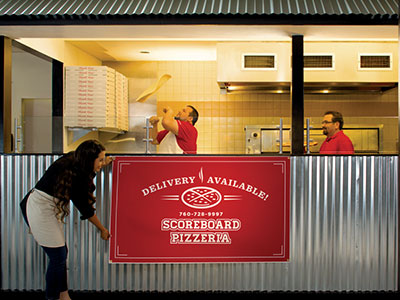 woman hanging a banner in front of a pizza shop